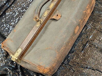 Eine geheimnisvolle alte Ledertasche mit roten Schlössern steht auf einem schwarzen Paillettentuch