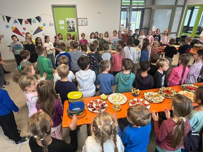 Viele Schulkinder stehen klatschend am Frühstücksbuffet