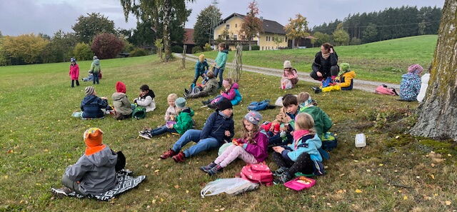 Die Schulkinder sitzen auf einer Wiese und machen eine Pause