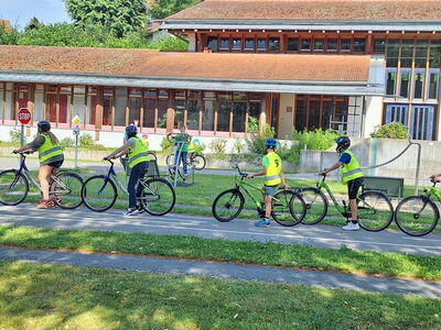 Schüler auf Fahrrädern warten hintereinander an einem Stoppschild