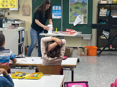 Frau Riedl steht vor der Klasse und zeigt ein Modell eines Zahnes