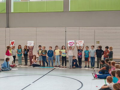 Grundschulkinder versammelt in der Turnhalle mit Plakaten